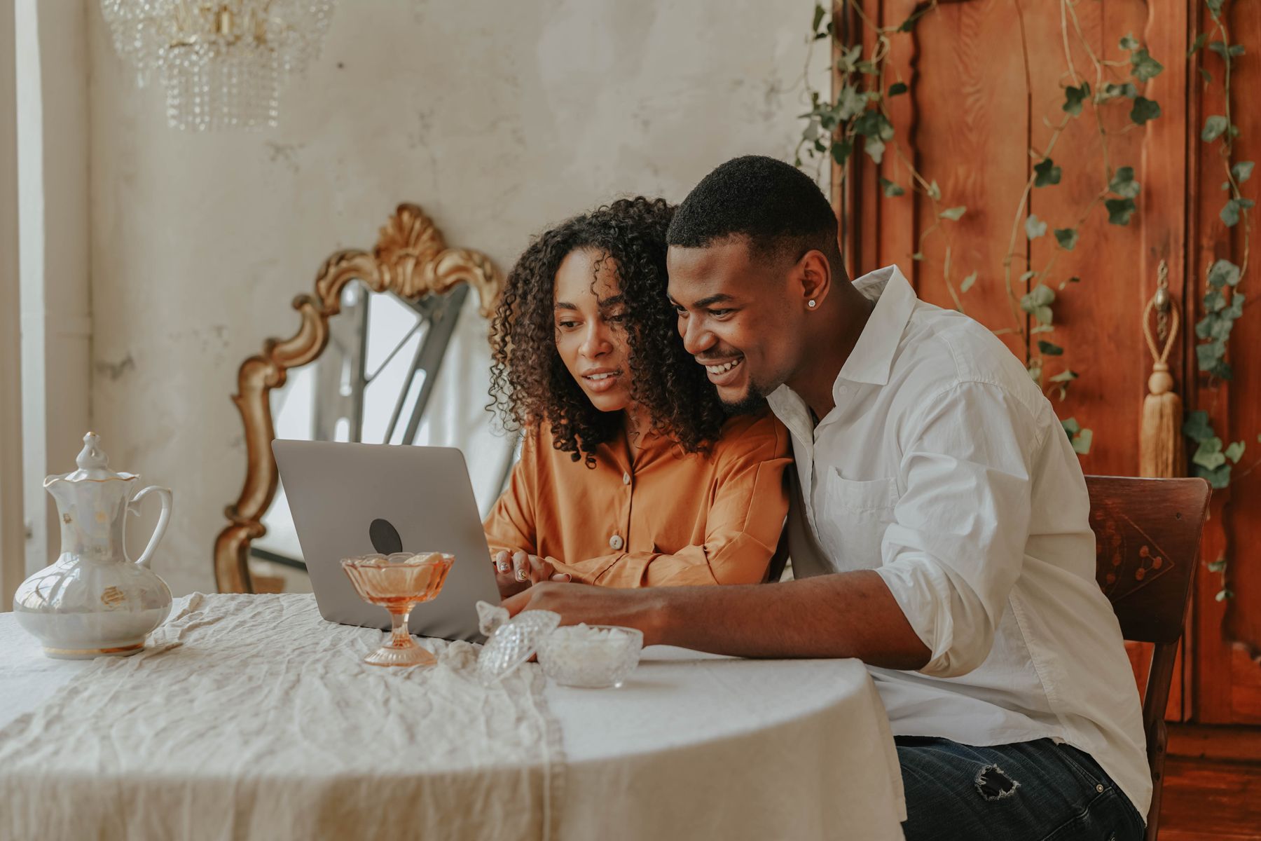 Dos personas compartiendo una laptop y sonriendo en casa